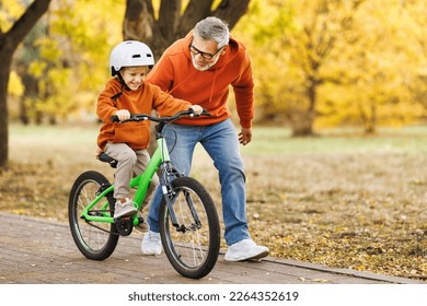 Happy family grandfather teaches boy grandson  to ride a bike in autumn park   in nature - Powered by Shutterstock