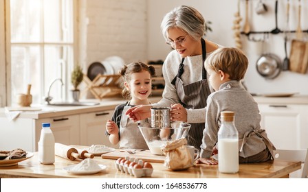 happy family grandmother and grandchildren cook in the kitchen, knead dough and bake cookies