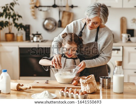 happy family grandmother and granddaughter child  cook in the kitchen, knead dough and bake cookies