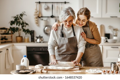glückliche Großmutter, alte Schwiegermutter und Schwiegertochter kochen in der Küche, Knetteig und Backwaren