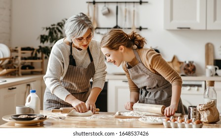 happy family grandmother  old mother mother-in-law and daughter-in-law daughter cook in kitchen, knead dough and bake cookies