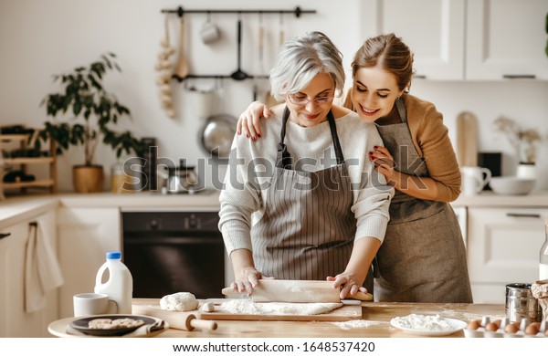 happy family grandmother  old mother\
mother-in-law and daughter-in-law daughter cook in kitchen, knead\
dough and bake cookies\
