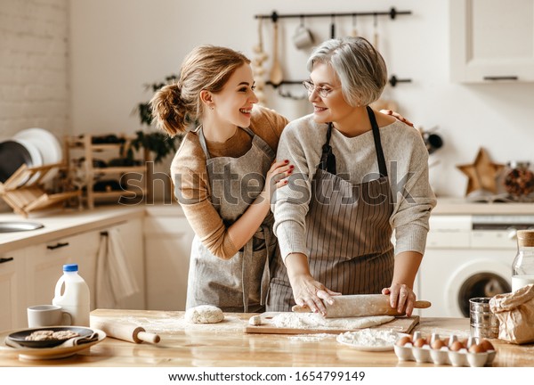 happy family grandmother  old mother\
mother-in-law and daughter-in-law daughter cook in kitchen, knead\
dough and bake cookies\
