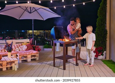 glückliche Familie grillt im Dachterrasse zu Hause in warmer Sommernacht
