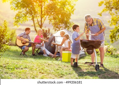 Happy Family Grilling Meat On A Barbecue
