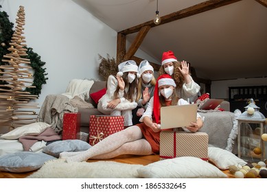 Happy family group of women wearing Christmas hats and protective face masks, take video calls during coronavirus pandemic.Coronavirus and Christmas concept.