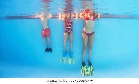 Happy Family Has Fun, Relax At Poolside After Swimming Lesson. Underwater Photo Of People Group In Pool. Healthy Lifestyle, Active Parents, People Water Sports Activities On Summer Holidays With Kids.