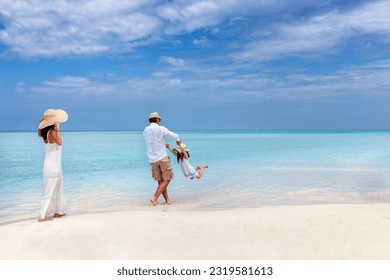 A happy family has fun in the turquoise ocean of a  tropical paradise beach in the Maldives during their holiday time - Powered by Shutterstock