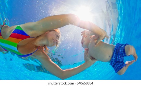 Happy Family Has Fun. Underwater Photo. Mother Teach To Swim And Dive Baby Son In Swimming Pool. Healthy Lifestyle, Active Parent, People Water Sport And Lessons On Beach Summer Holiday With Child.