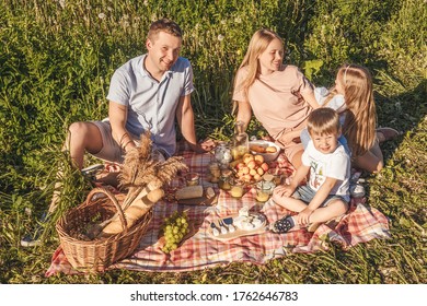 Happy family have a rest together in a picnic outdoors. Blue pink clothes, casual. Beautiful mother, father and children. - Shutterstock ID 1762646783