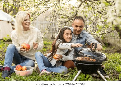 Happy family having a barbecue in their garden in spring. Leisure, food, family and holidays concept. - Powered by Shutterstock