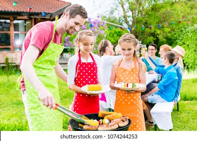 Happy Family Having Barbeque At Garden Party