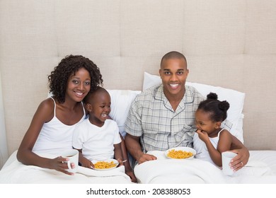 Happy family having breakfast in bed together in the morning at home in the bedroom - Powered by Shutterstock