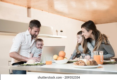 Happy family having breakfast , father on laptop with baby