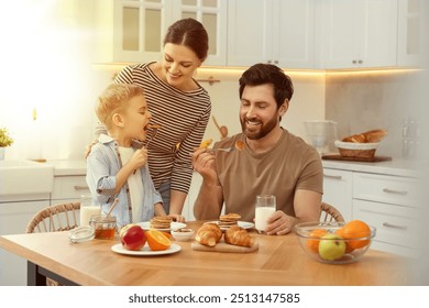 Happy family having breakfast at table in kitchen on sunny morning - Powered by Shutterstock