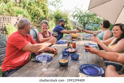 Happy Family Having Fun At Barbecue Outdoor In The Garden - Multi Generational People Cheering With Red Wine