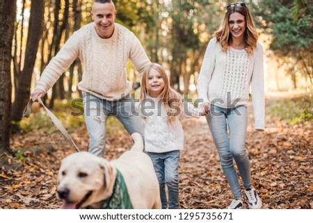Happy family is having fun with dog labrador outdoors.
