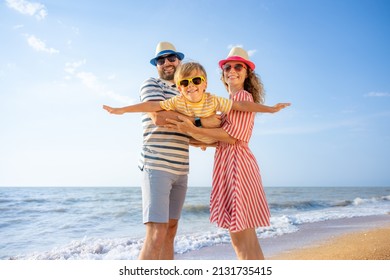 Happy family having fun on the beach. Mother and father holding son against blue sea and sky background. Summer vacation concept - Shutterstock ID 2131735415