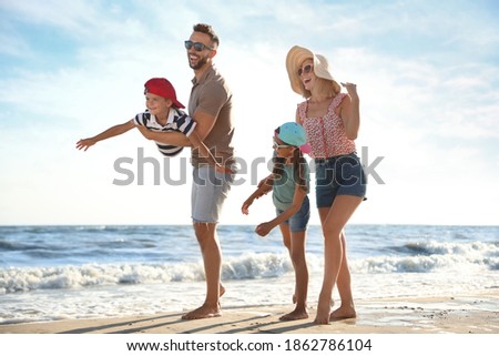 Happy family having fun on sandy beach near sea