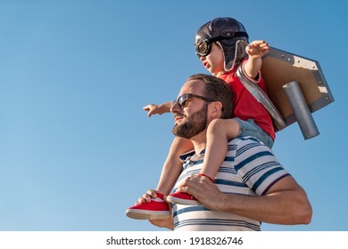 Happy family having fun outdoor. Father and son playing against blue summer sky background. Imagination and freedom concept