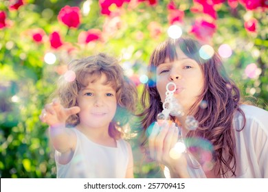 Happy Family Having Fun Outdoors In Spring Park Against Natural Green Background