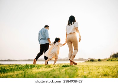 Happy family having fun and playing together on a summer vacation, running and laughing in the nature, with the sun and green grass all around them, family day - Powered by Shutterstock