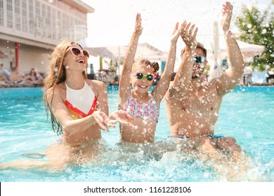 Happy Family Having Fun In Pool On Sunny Day