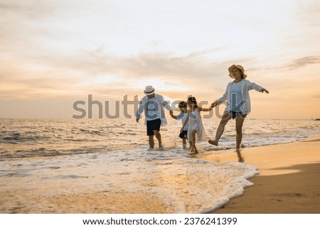Happy family having fun running on a sandy beach at sunset time, Active parents and people father, mother, children son and daughter holding hands together walking on beach, tropical summer vacations