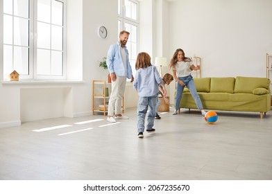 Happy Family Having Fun Together. Mother, Father And Children Playing Football With Toy Ball At Home. Mommy, Daddy And Little Kids Playing Soccer In Modern Living Room Of Their New House