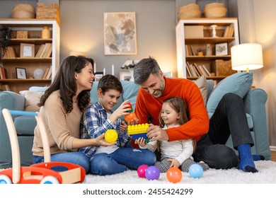 Happy family having fun with toys, parents and little children sit on sofa together, Happy family sitting on sofa playing together. Cheerful parents playing with their kids at home. - Powered by Shutterstock