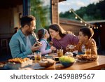 Happy family having fun while eating at dining table on a patio in spring day. 