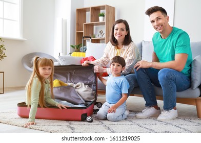 Happy family having fun while packing suitcase at home