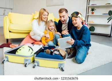 Happy Family Having Great Time, Using Digital Tablet And Packing For Winter Holidays