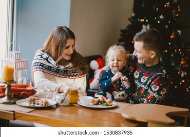 Happy family having holiday breakfast on Christmas morning.