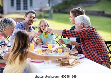 Happy Family Having Lunch In The Garden On A Sunny Day