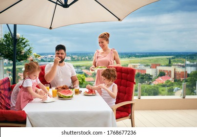 Happy Family Having Lunch On Rooftop Patio At Home