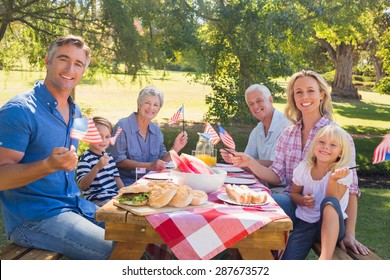 Happy family having picnic and holding american flag on a sunny day - Powered by Shutterstock