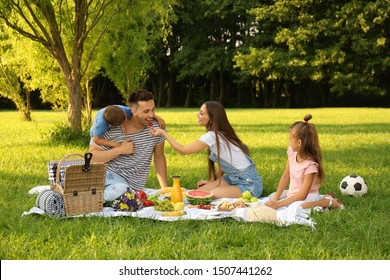 Happy family having picnic in park on sunny summer day - Powered by Shutterstock