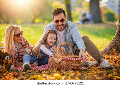 Happy family having picnic in park.Young happy family of three having fun together.Family fun outside. - Powered by Shutterstock