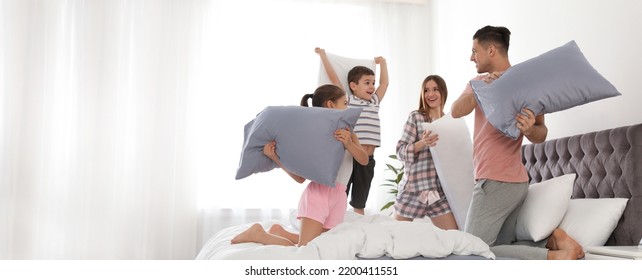 Happy family having pillow fight in bedroom, space for text. Banner design - Powered by Shutterstock