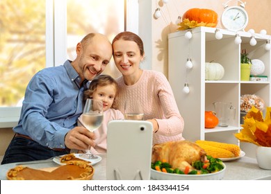 A happy family is having a thanksgiving dinner, holding a glass of wine and saying cheers to their parents , on a video conference call - Powered by Shutterstock