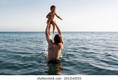 Happy Family And Healthy Lifestyle. A Young Father Teaches A Child To Swim In The Sea