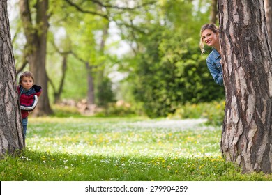 Happy family hiding behind trees while playing in a park