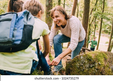 Happy family are hiking through the woodlands together. The mother has stopped to help her son tie the laces on his hiking boots. - Powered by Shutterstock