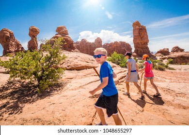 happy family hiking together in the beautiful rock formations of Arches National Park. Walking along a scenic trail with large rock unique formations in the background