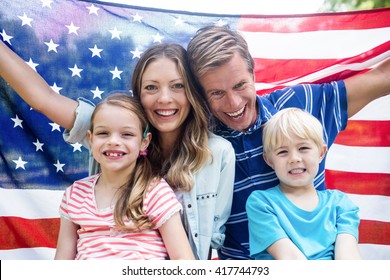 Happy family holding american flag in the park on a sunny day