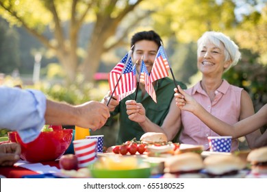 Happy family holding american flags while having meal in the park