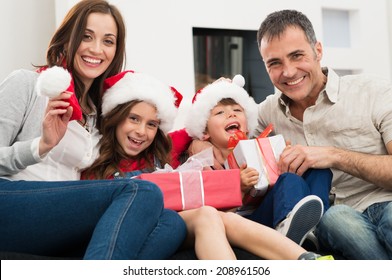 Happy Family Holding Christmas Gift Looking At Camera