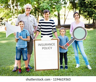 Happy Family Holding Up Insurance Policy Board