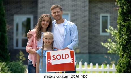 Happy Family Holding Sold Sign, Standing Against New Bought House, Thumbs Up